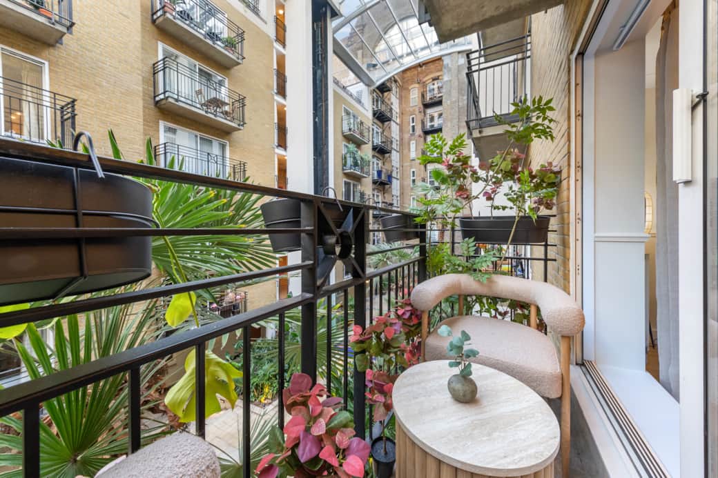 Cozy balcony with seating, lush plants and tranquil courtyard view Cozy balcony with seating, lush plants and tranquil courtyard view