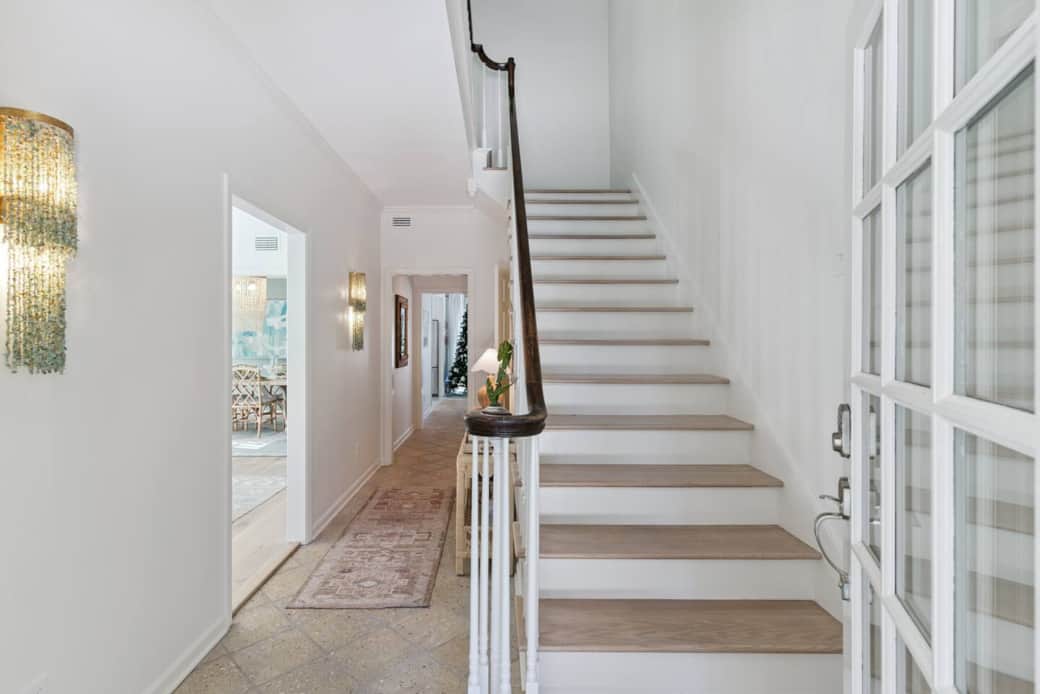 The house opens up into the foyer with the main hallway on the left and stairs to the right. 