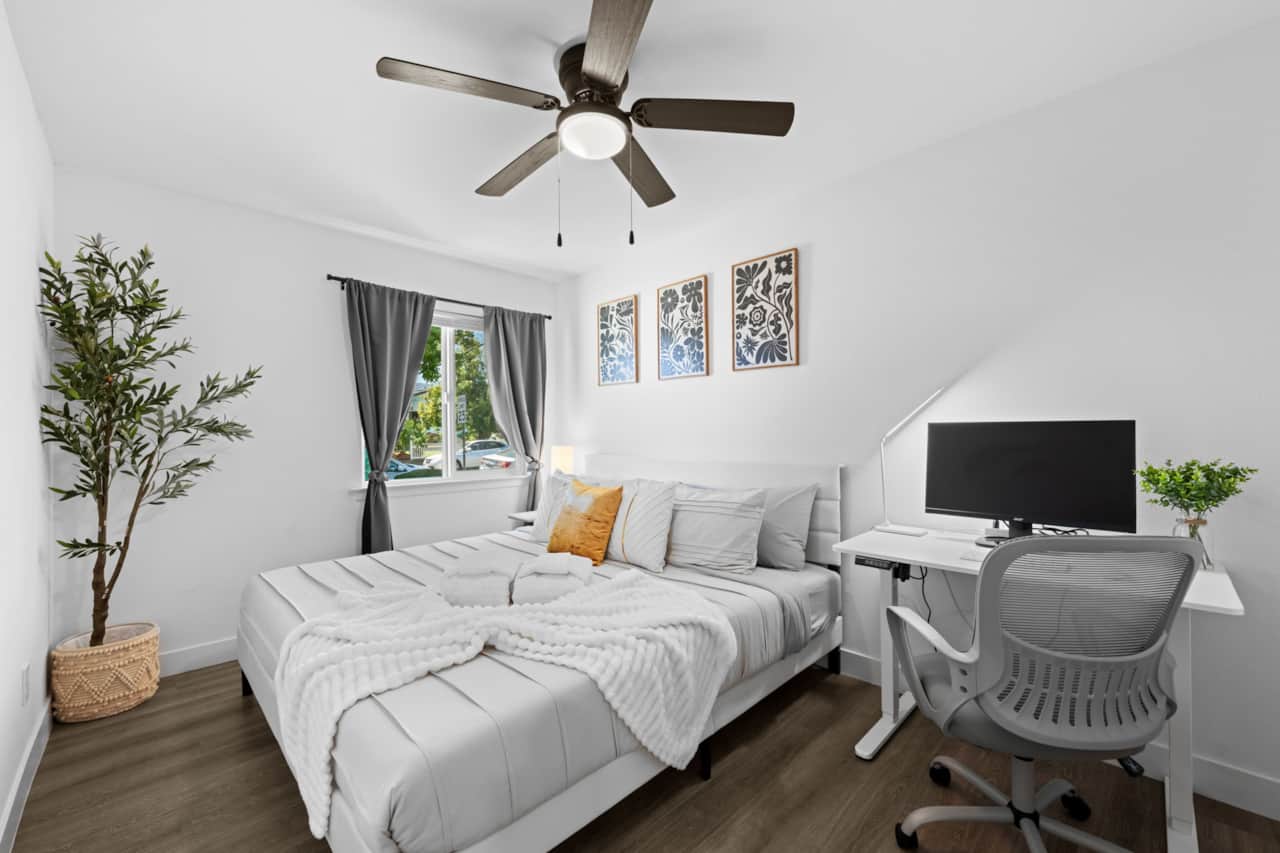 Bright, modern bedroom with a comfortable King bed, desk workspace, ceiling fan, and stylish decor