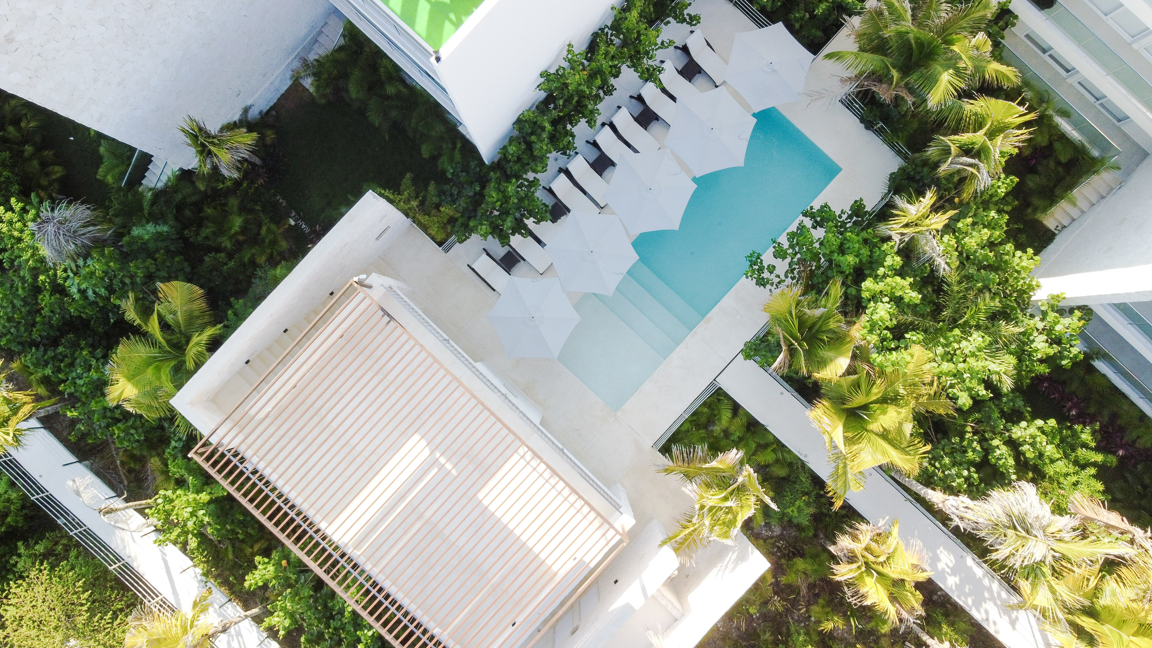 Aerial view of the resort with lush grounds, a serene pool, and a peaceful rooftop yoga deck.