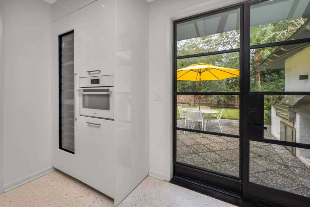 The kitchen features a full size wine fridge, Miele microwave, and easy access to the outdoor grill and dining area! 