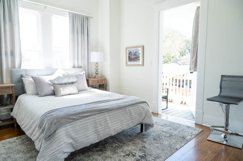 Queen bedroom with balcony access, makeup station, and soft lighting inside White Magnolia Galveston