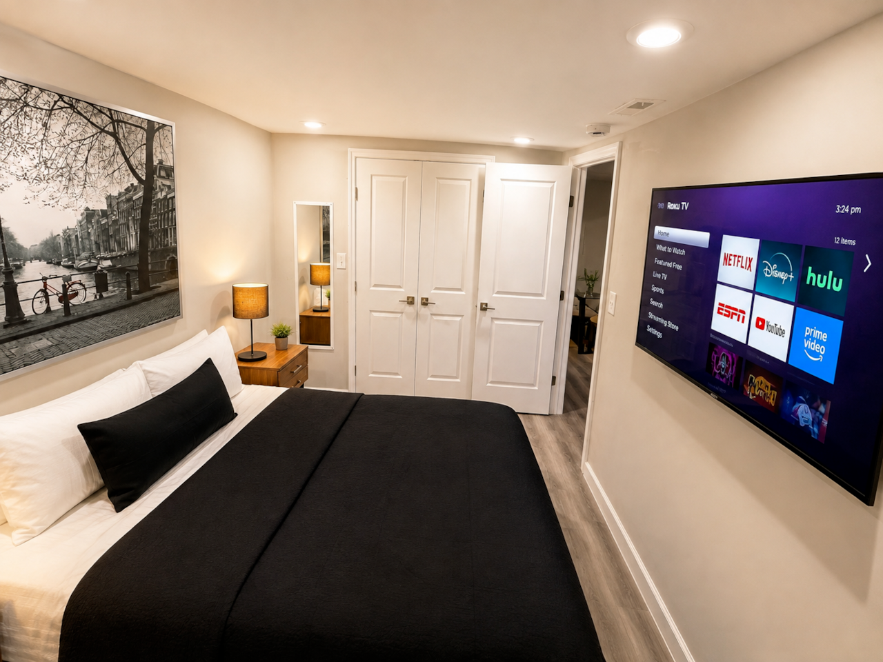 Bedroom 1: Comfortable, stylish bedroom featuring a queen-size bed, crisp bedding, warm bedside lighting, and a wall-mounted Smart TV with Roku. The room also offers a large closet with plenty of storage space, modern flooring, and relaxing décor—perfect for a comfortable stay.