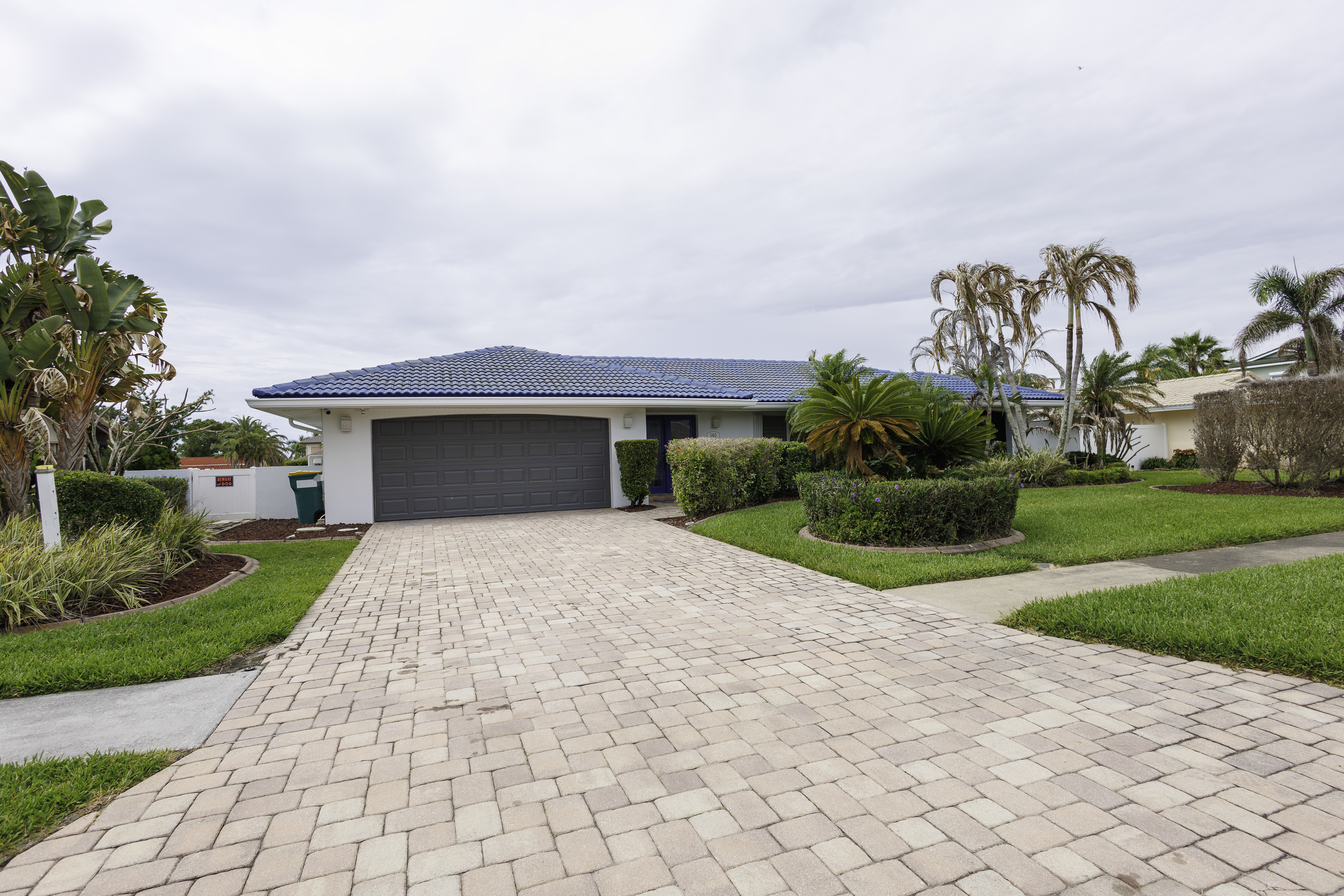 Arrive at a well-kept home with a spacious paved driveway and tropical landscaping.