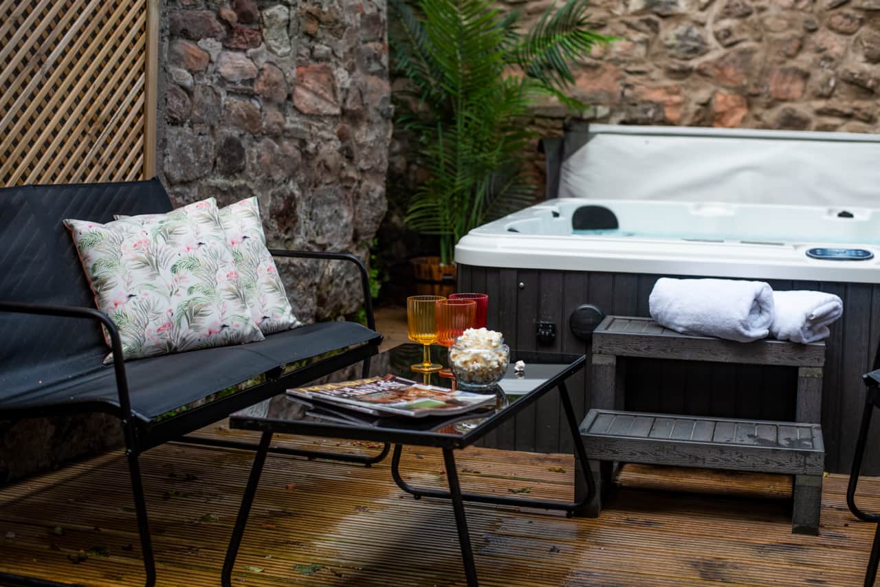 Private hot tub enclosed by stone/wood. Relax on the deck under a canopy with black seating