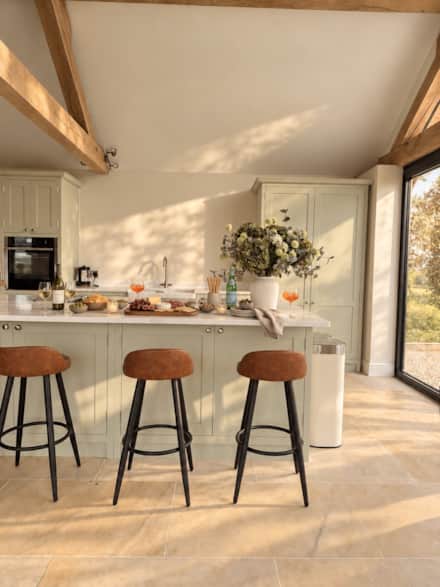 Sage green kitchen, oak beams and limestone floor at The Cotswold Barn