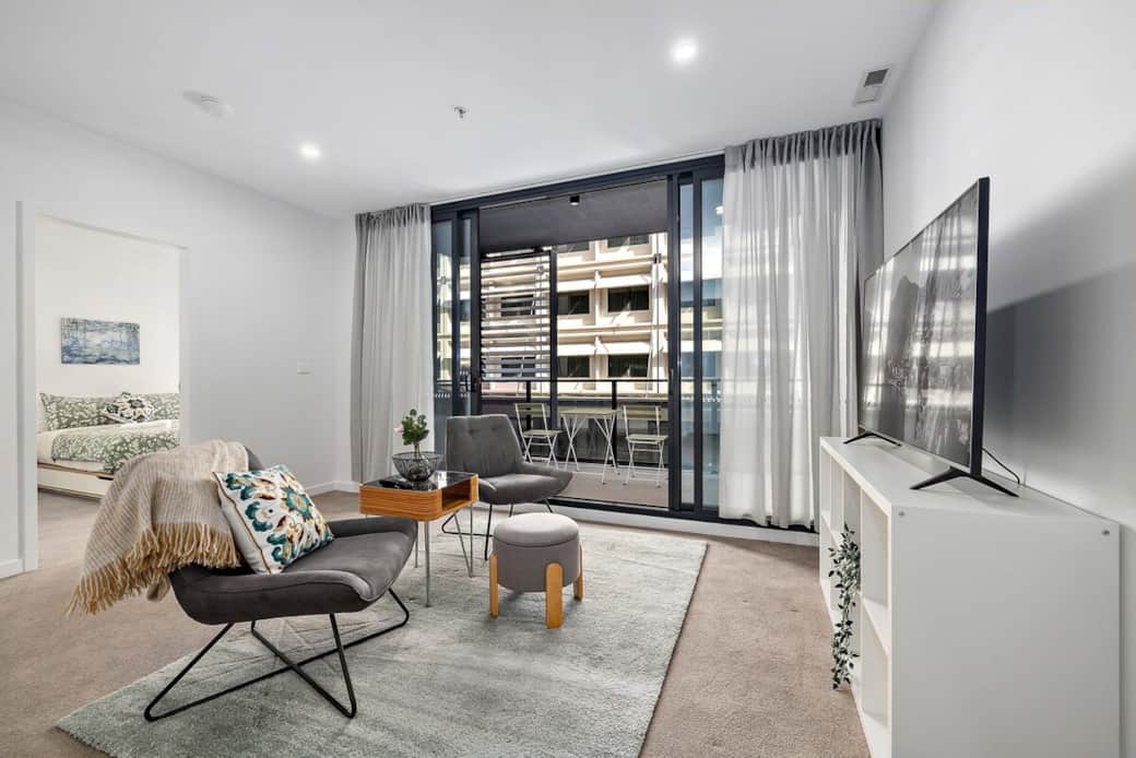 Our living room is a haven of comfort and style, bathed in natural light from the large windows. The modern furniture, including a plush sofa and armchairs, invites relaxation. Enjoy the convenience of a flat-screen TV and a cozy rug underfoot. 