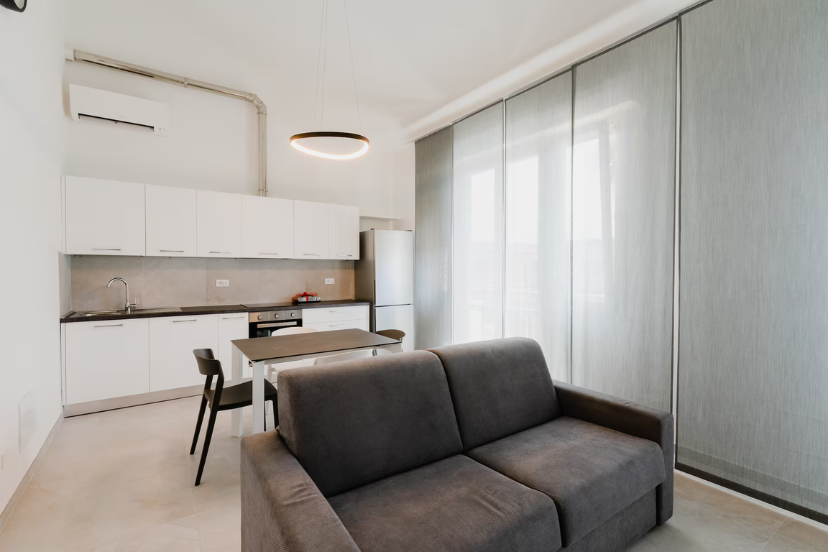 Soggiorno open space CasaGiallo Versilia: zona living con cucina attrezzata e divano letto, interni moderni