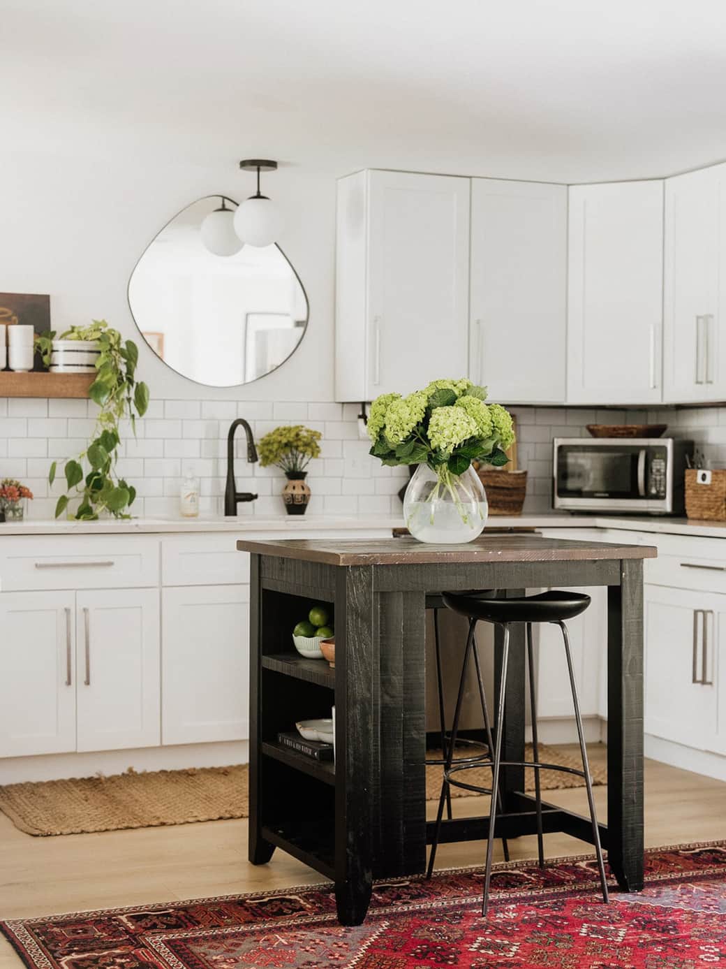 A bright, thoughtfully designed kitchen featuring a stocked spice cabinet, elevated coffee bar with Nespresso Vertuo and Essenza machines with corresponding pods, and to-go cups. Complete with a Ninja blender, and virtually all cooking staples. 