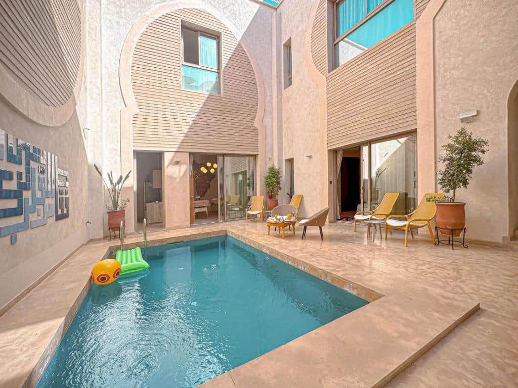 Piscine au cœur du patio du Riad Timija, entourée d’espaces de détente partagés.