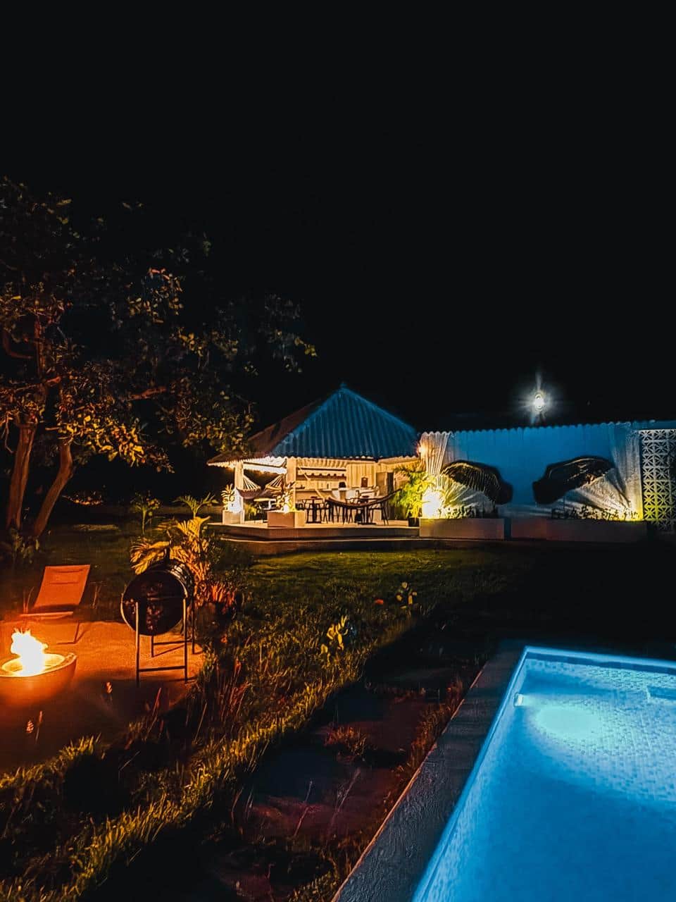 Pool glowing at night with fire pit and covered lounge at an eco retreat in Coronado, Panama