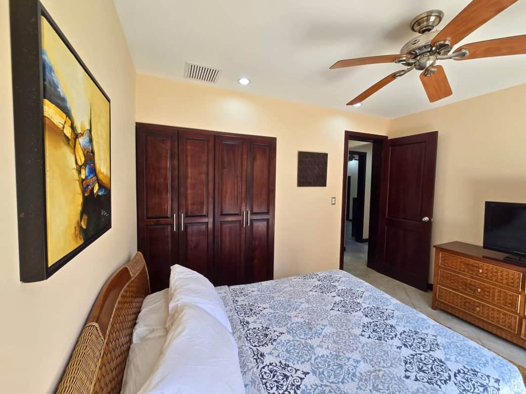 Comfortable second bedroom with queen bed, blackout curtains, cable TV, and sliding glass door to a quiet patio. Ideal for restful nights and relaxed mornings.