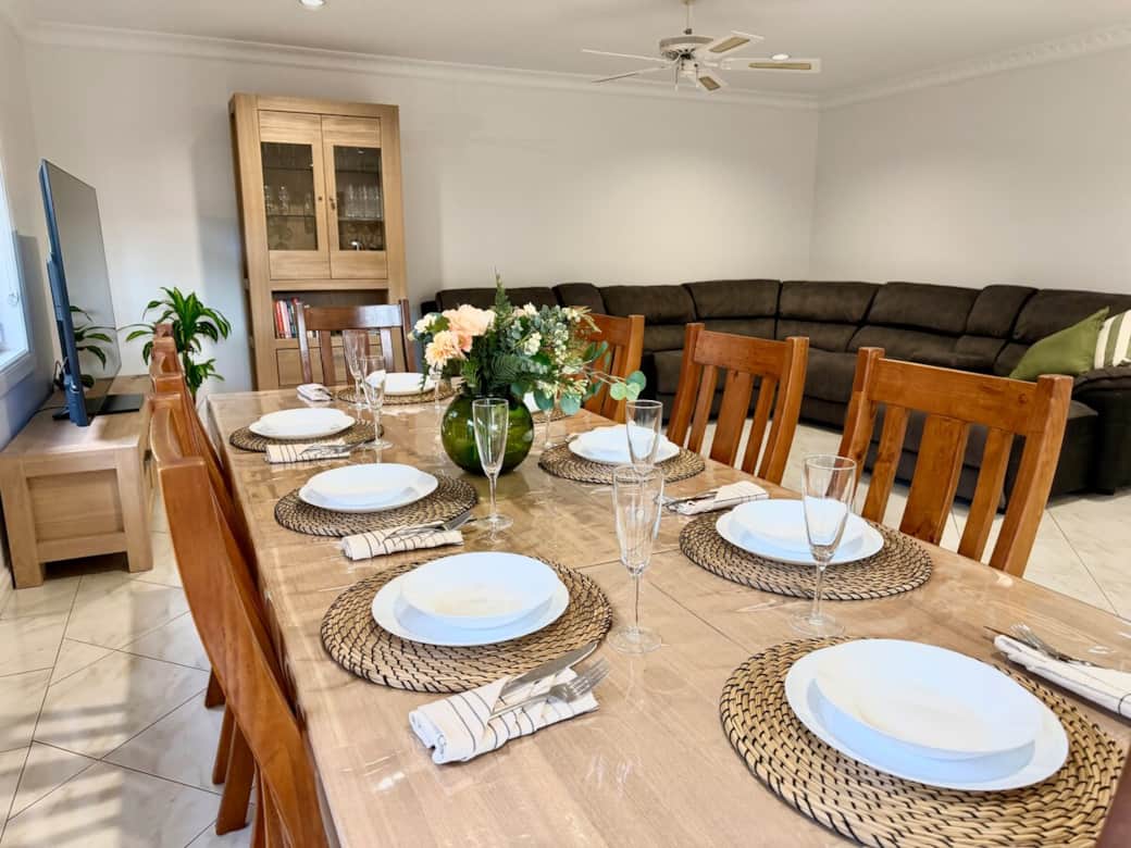 Beautiful dining area set for a shared meal, featuring a spacious wooden table, comfortable seating for eight, and a cosy open-plan layout perfect for gathering with family and friends.