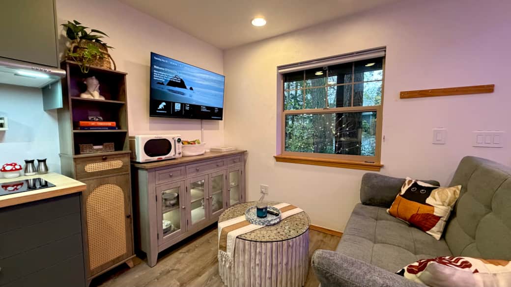 Relax in the living room with a sofa that easily converts into a bed, warm lighting, and a smart TV 