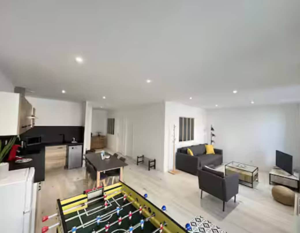 Salon lumineux avec canapé confortable, TV et table de jeu – idéal pour se détendre ou partager des soirées en famille.