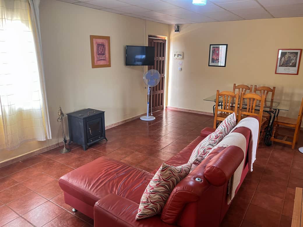 Sala de estar con sofá, TV de pantalla plana y estufa de leña controlada