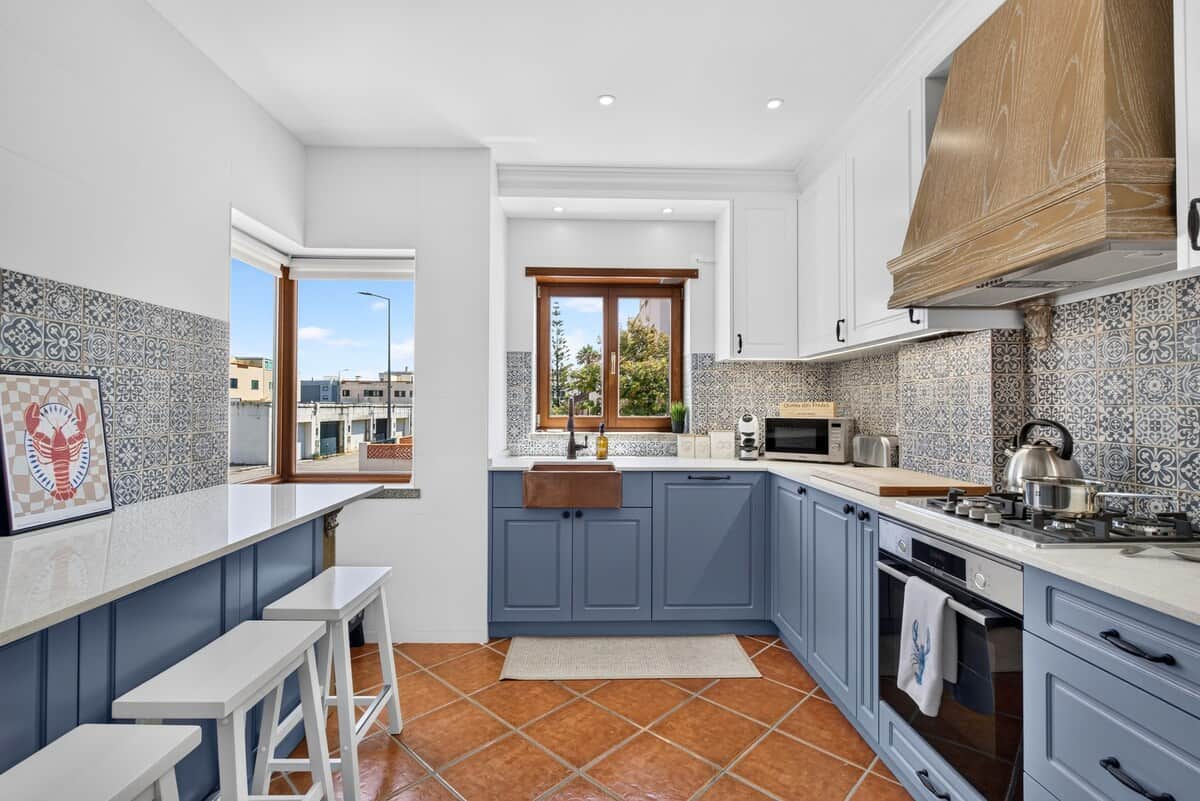 Fully equipped modern kitchen featuring a copper sink, breakfast bar, and traditional tiles.