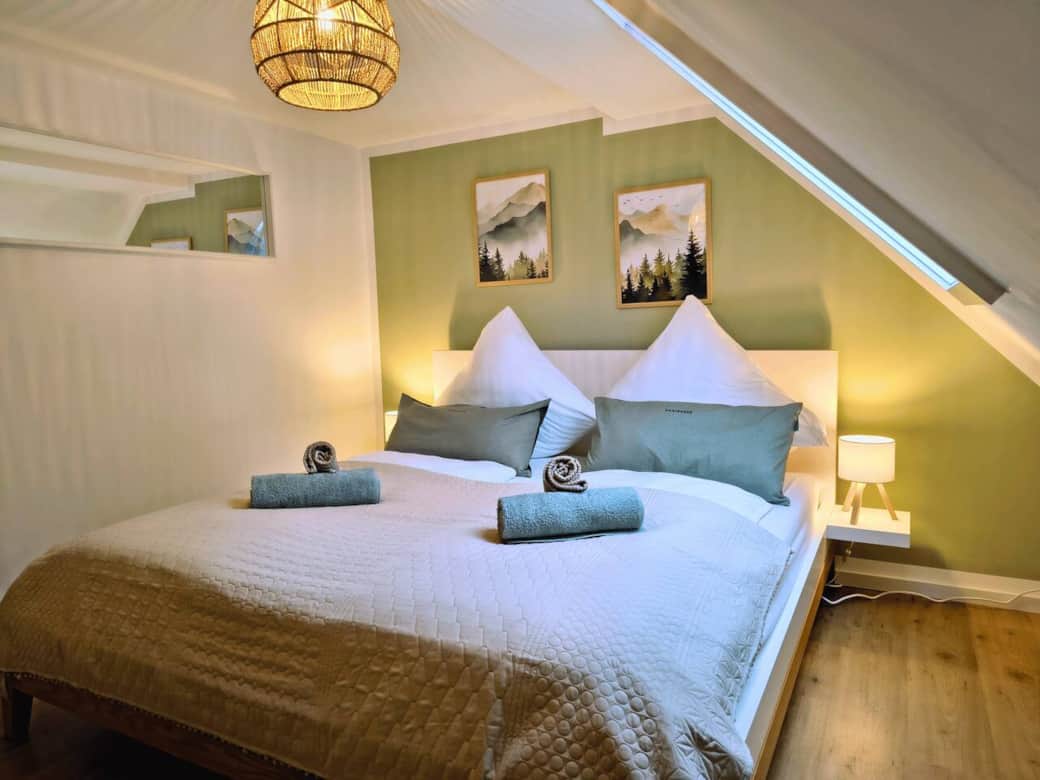 Kuscheliges Schlafzimmer unter dem Dach mit gemütlichem Doppelbett, warmem Licht und Wanddeko im Harz-Naturstil – perfekt zum Ausschlafen nach einem aktiven Tag. Kuscheliges Schlafzimmer unter dem Dach mit gemütlichem Doppelbett, warmem Licht und Wanddeko im Harz-Naturstil – perfekt zum Ausschlafen nach einem aktiven Tag.