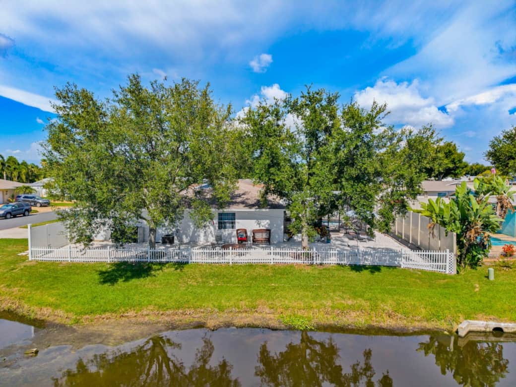 The side yard overlooks a peaceful lake and is shaded by mature oak trees, creating a private, tranquil setting. A fenced yard and lush greenery provide the perfect backdrop for relaxing and enjoying Florida's natural beauty.