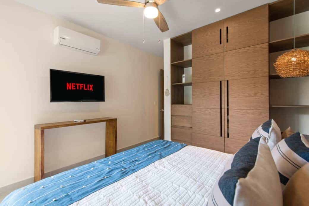 Cozy bedroom with AC, ceiling fan, smart TV, and full wardrobe.