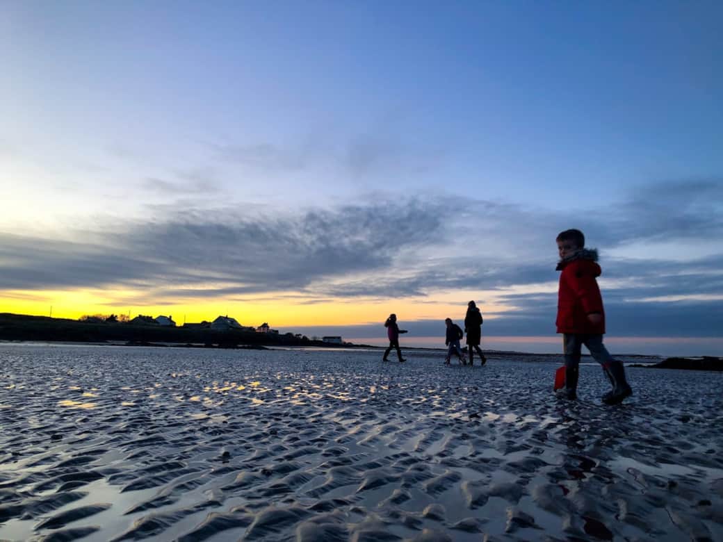 Family walks on the beach at sunset