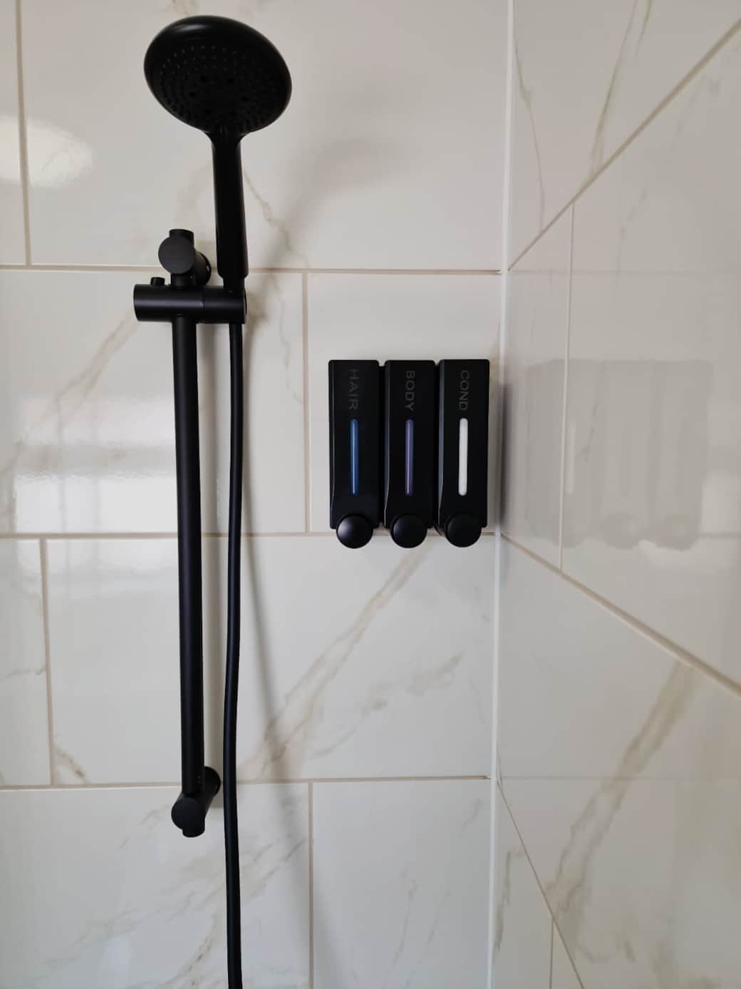 Modern shower with complimentary shampoo, conditioner and body wash.