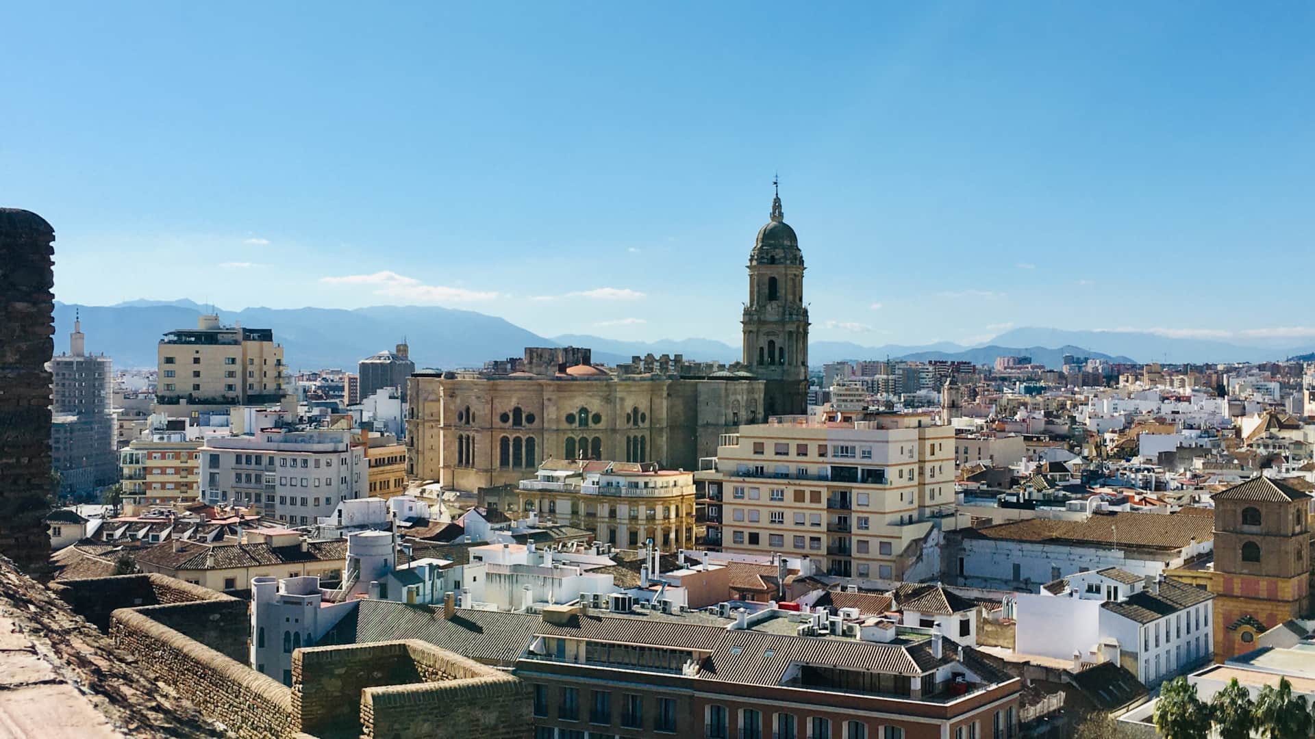Panoramic view of Málaga with the Cathedral and mountains in the background on a clear sunny day.