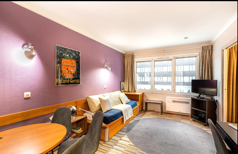 Salon avec deux lits simples, table à manger pour 4, et TV connecté