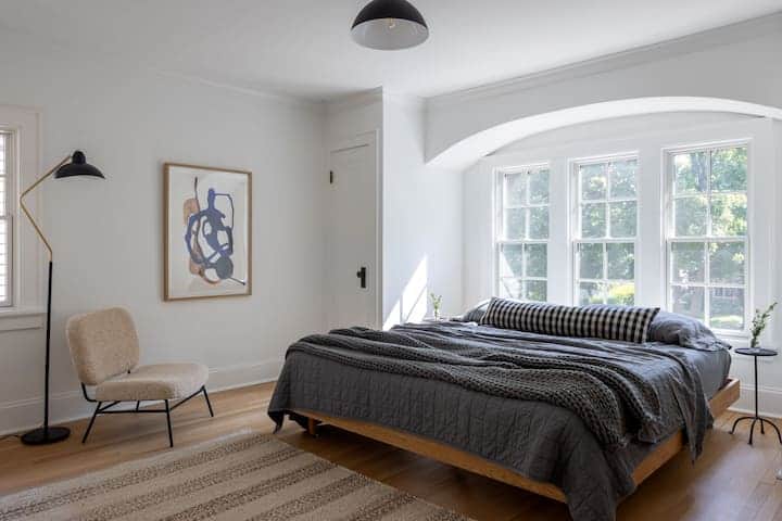 Peaceful bedroom with soft natural light, cozy layered bedding, and charming architectural details.