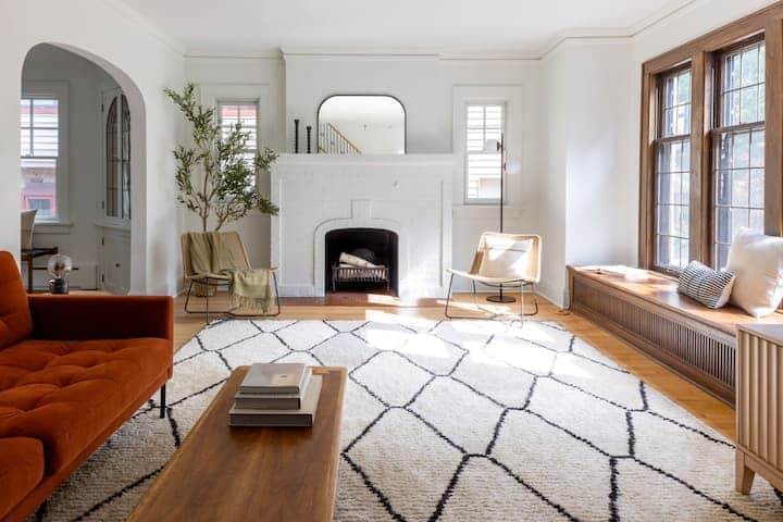 Bright and beautifully styled living room with a classic fireplace, large windows