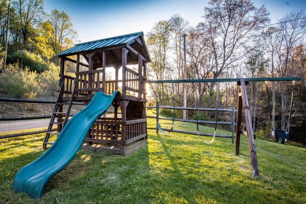 Play set with swings and climbing wall for the kids, inside a fully fenced yard