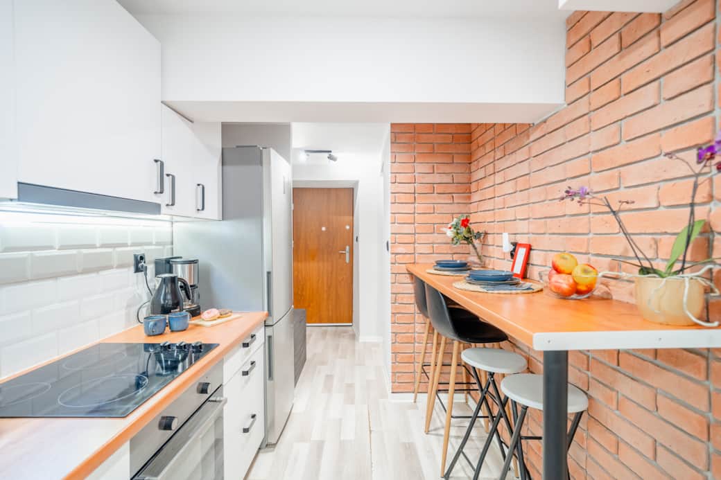 Nowoczesna kuchnia z pełnym wyposażeniem, wygodnym blatem jadalnianym i jasnym wykończeniem.