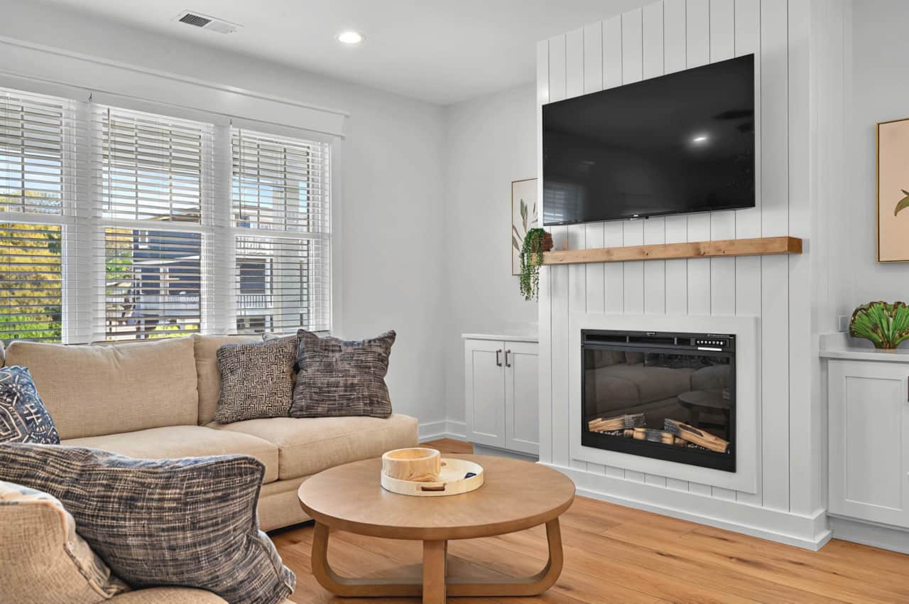 Spacious and well-lit living room with Smart TV, electric fireplace and games in the cabinets.