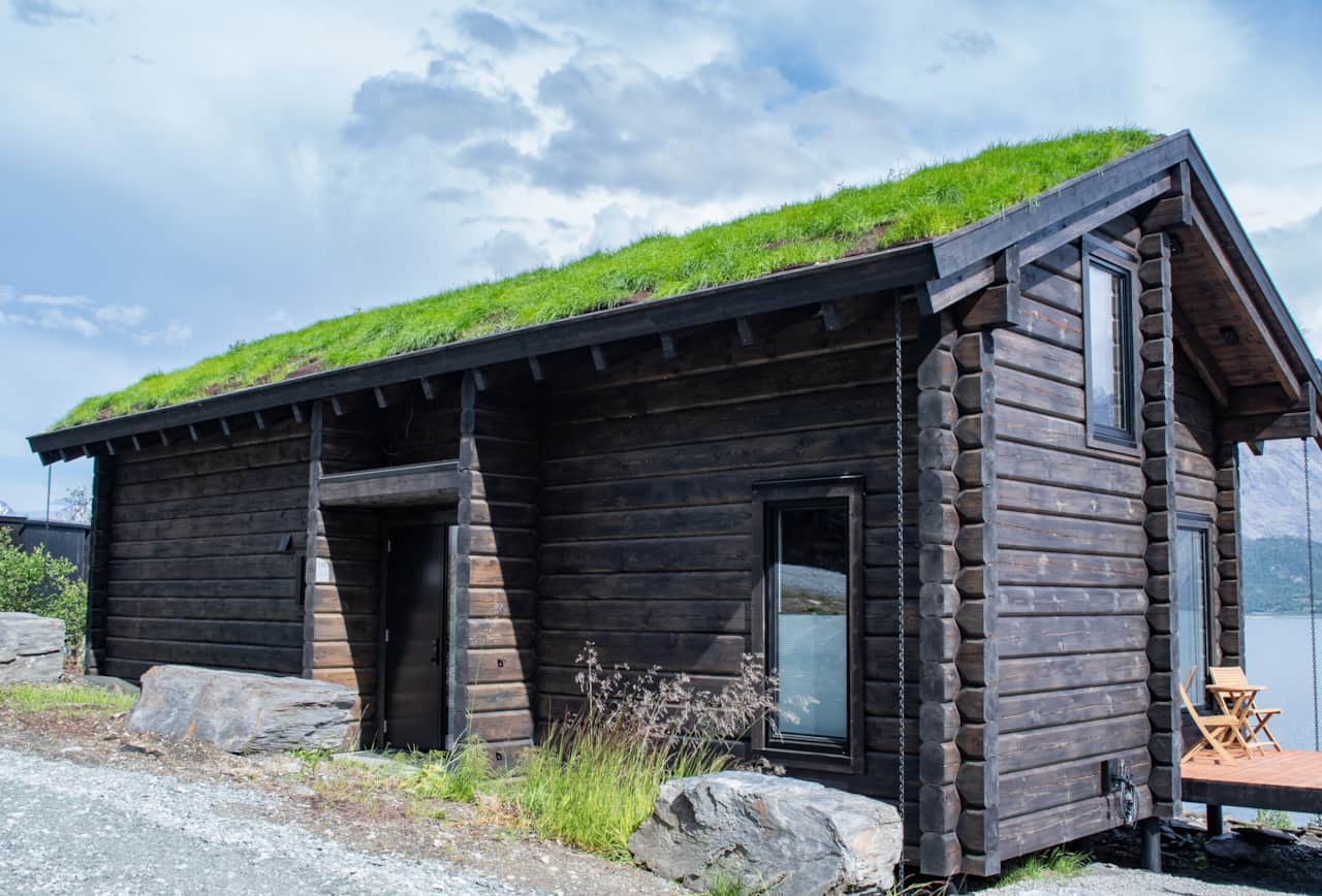 Full log timber, weathered dark. The facade of Skaret on the Ulsfjord.