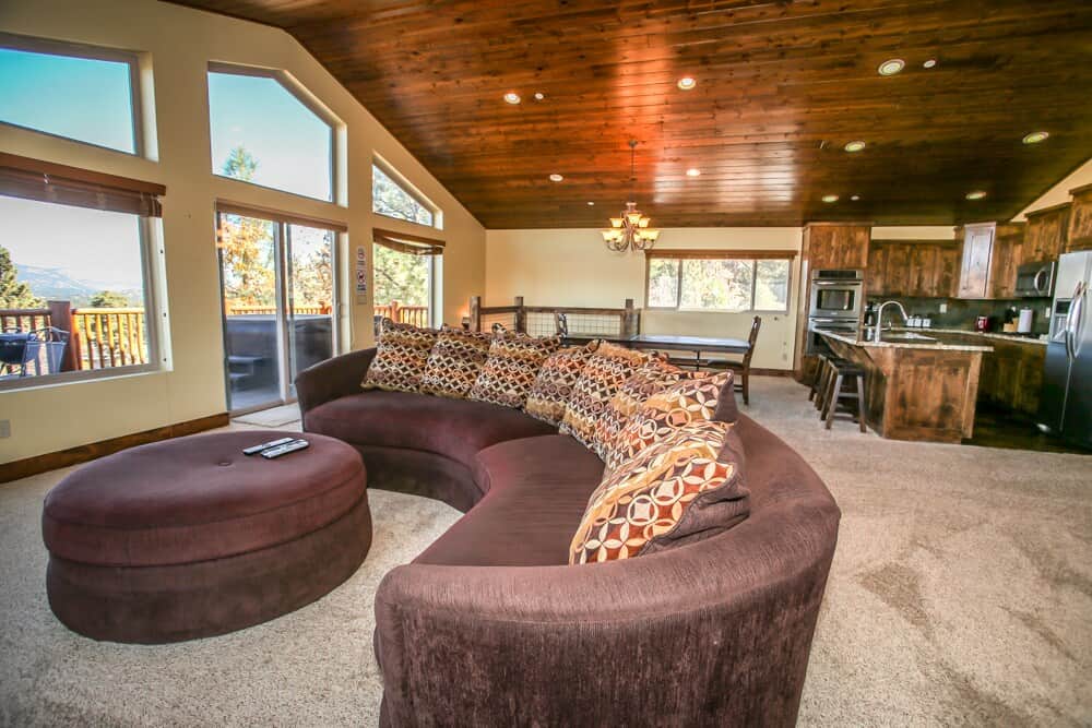 This room features gorgeous views of all of Big Bear! You can see the alpine slide, Big Bear Blvd, the lake, and the mountains! This room is also great for large groups. A beautiful, modern kitchen and bar can been seen in the background.
