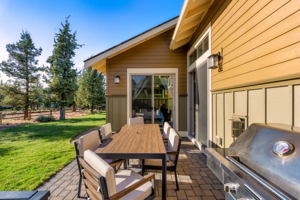 Private patio with dining set for six, KitchenAid grill, and ponderosa pine backdrop.