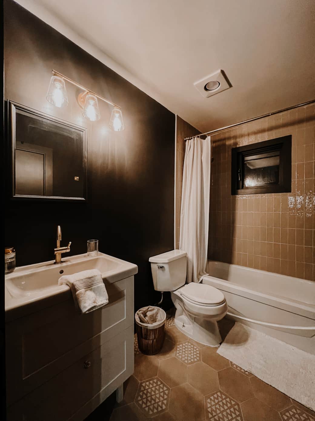 Warm, rustic shared bath with dark tones and luxury farmhouse charm.