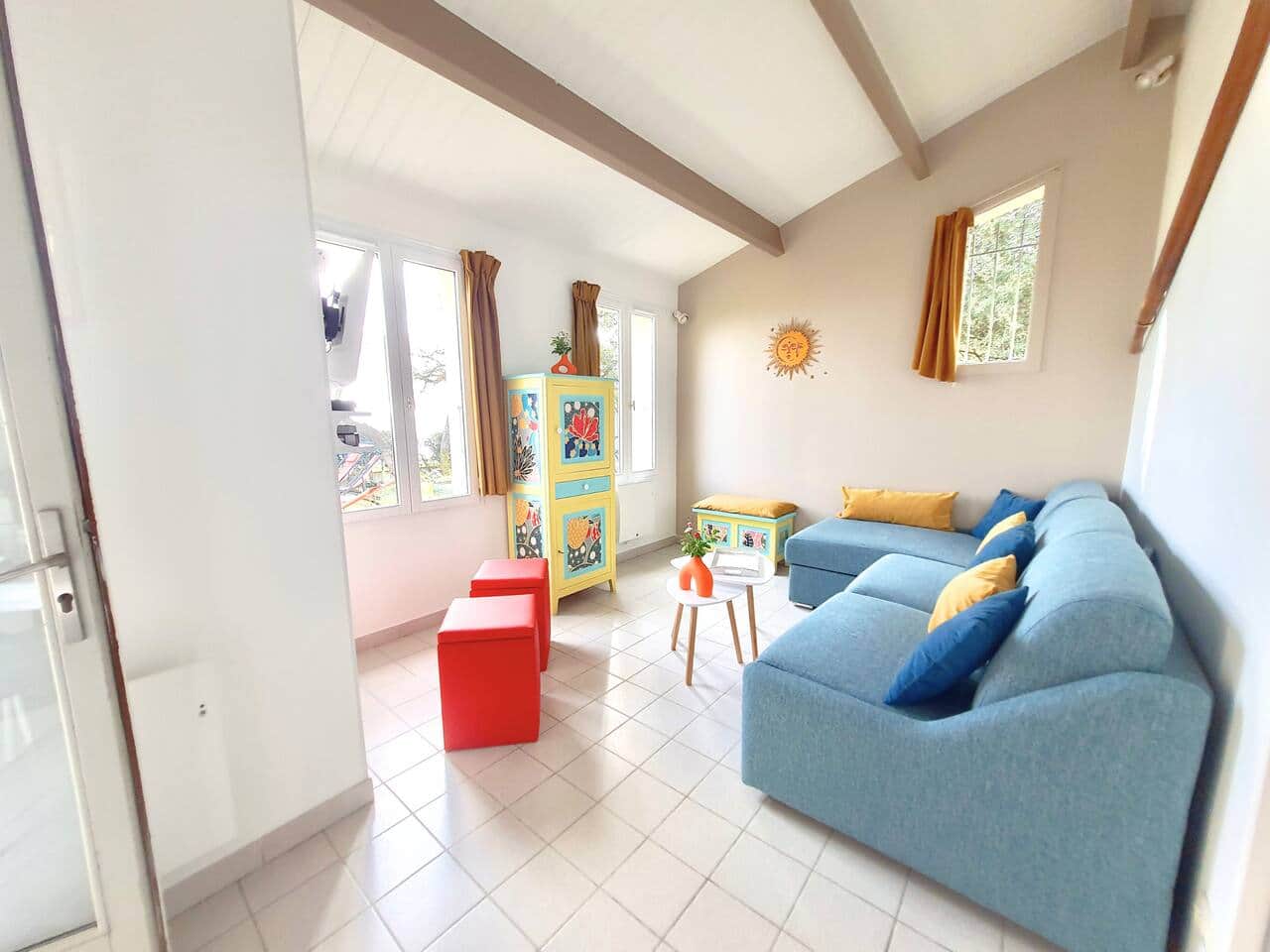 Un espace de vie baigné de lumière, avec vue sur l’extérieur et une décoration vive et chaleureuse. Idéal pour des moments de convivialité en famille ou entre amis.