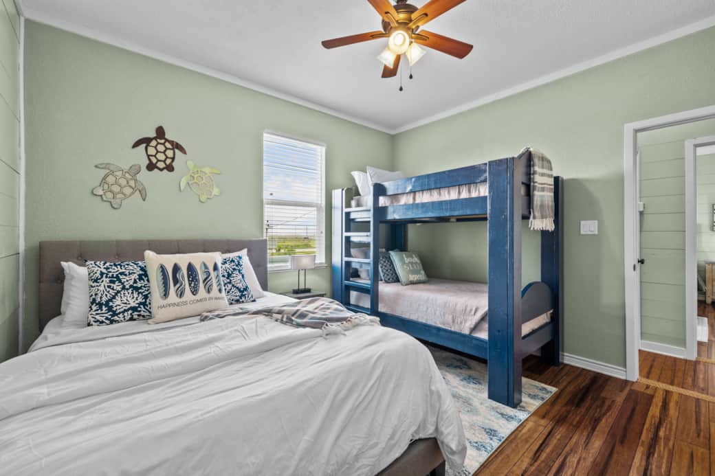 Second bedroom includes a queen bed and a twin bunkbed. The room also includes a charging port lamp.