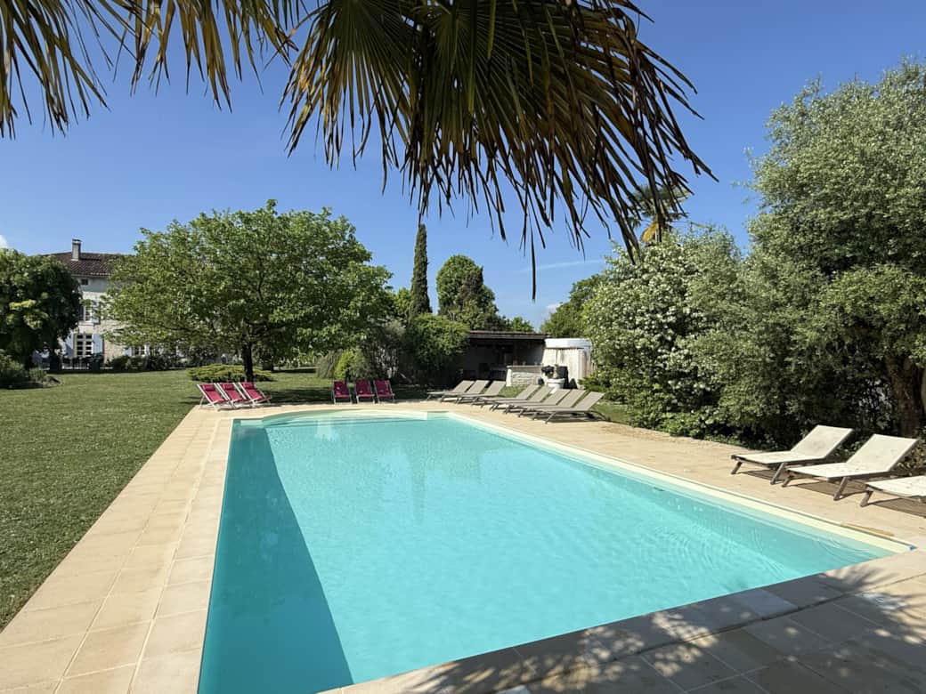 Vue de la piscine avec transats et pool house