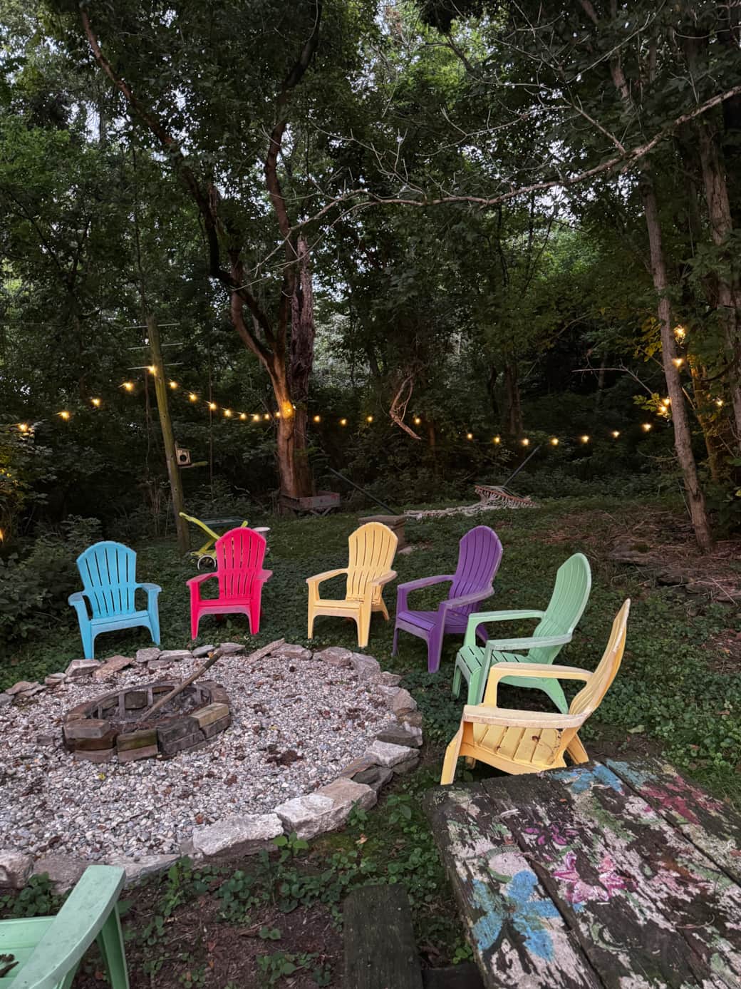 Outdoor firepit with 8 chairs and lighted glen with hammock for relaxing and gathering.