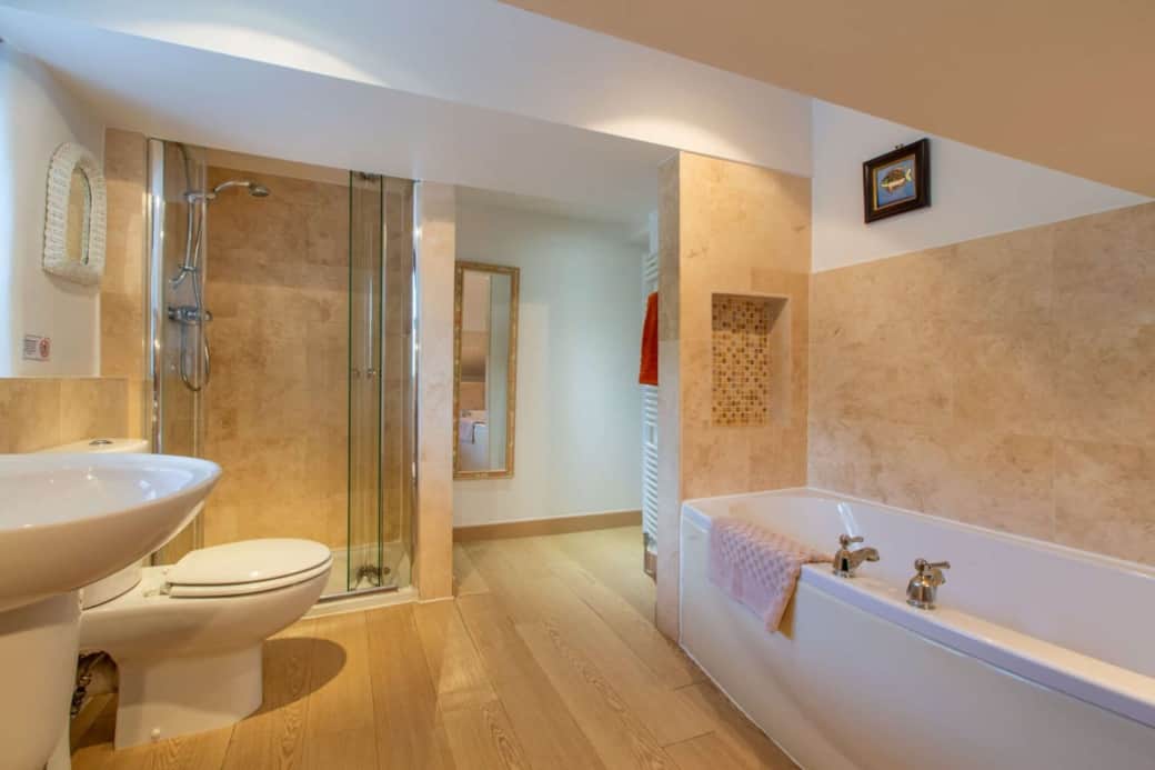 Bedroom 1's large ensuite bathroom with bath, separate shower cubicle, basin & toilet