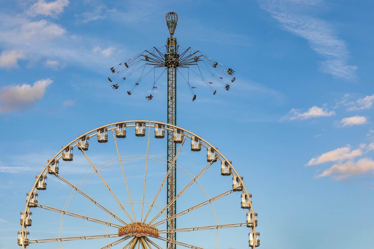 Riesenrad und Kettenkarussell vor blauem Himmel auf einem Volksfest