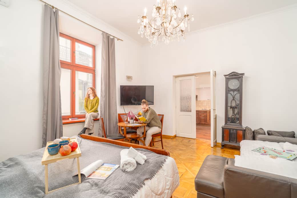 A bright, high-ceilinged room with a large window and an elegant chandelier creates .