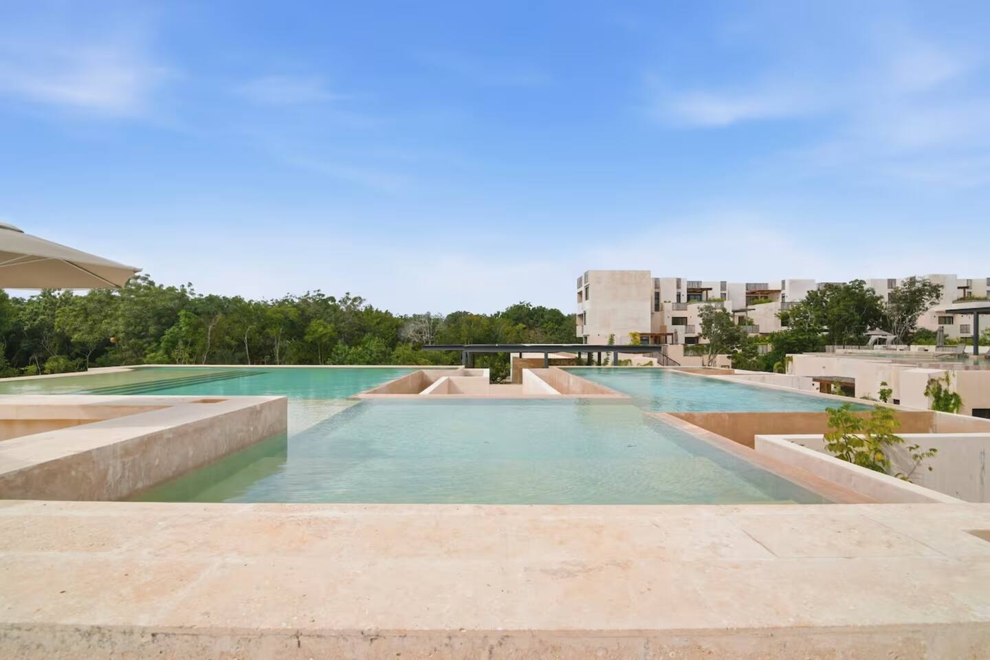 Una de las 4 albercas infinity de Gran Tulum, con hermosas vistas a la exuberante selva de Tulum: un lugar tranquilo para nadar, relajarte y disfrutar el entorno tropical.