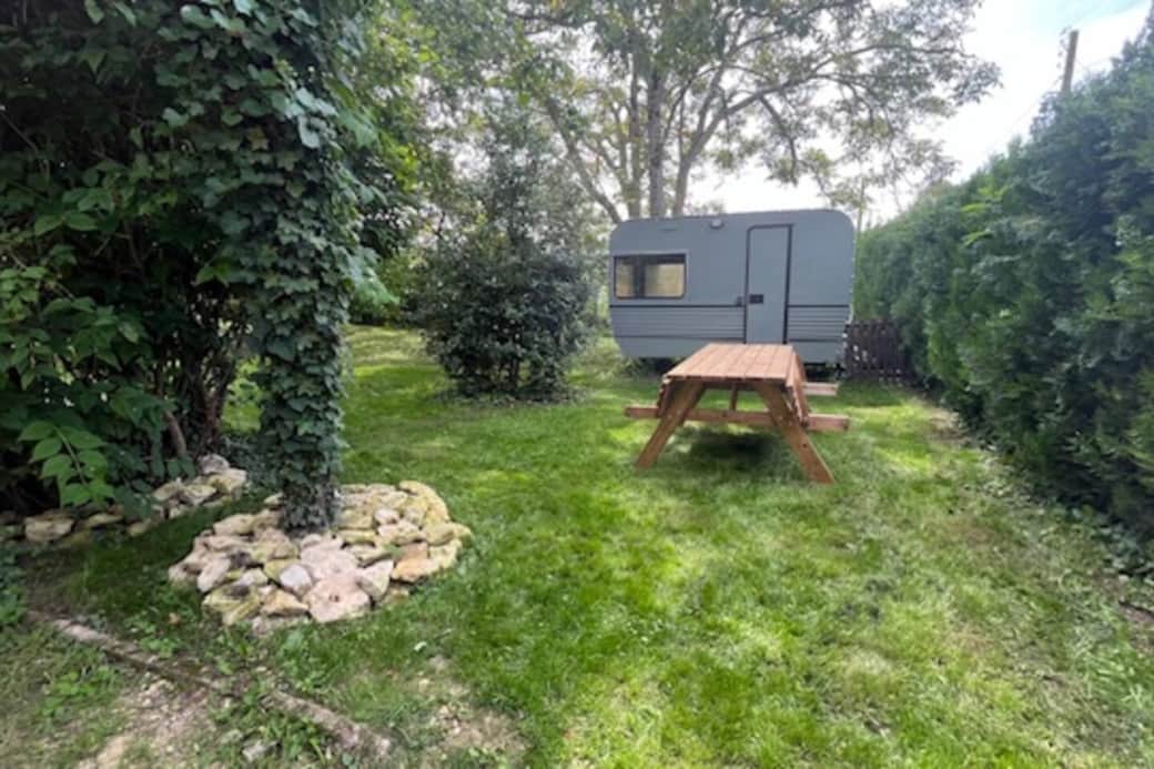La caravane fait office de cabane de jardin pour le rangement du mobilier extérieur 