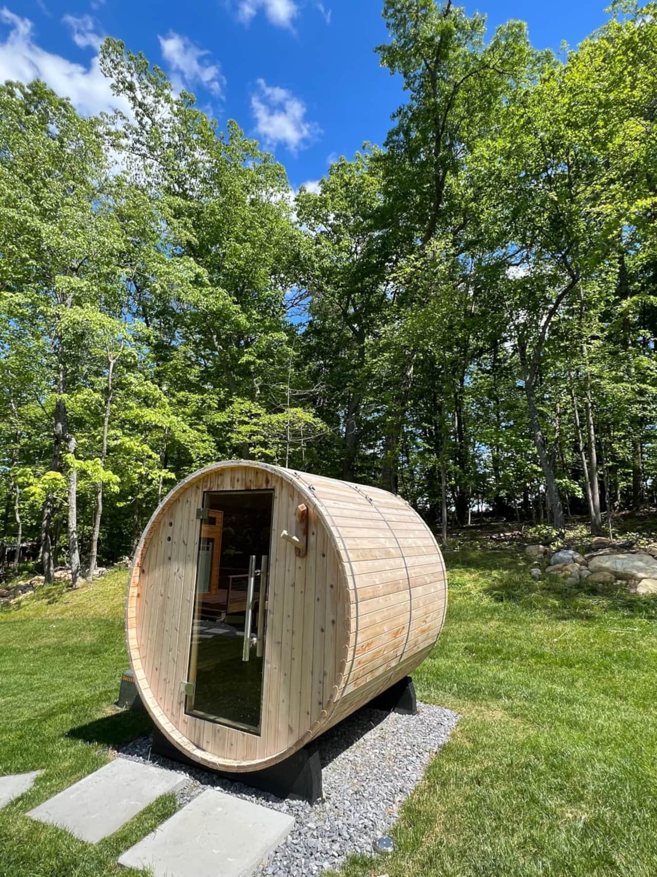 Traditional Nordic cedar barrel sauna set at the edge of the woods