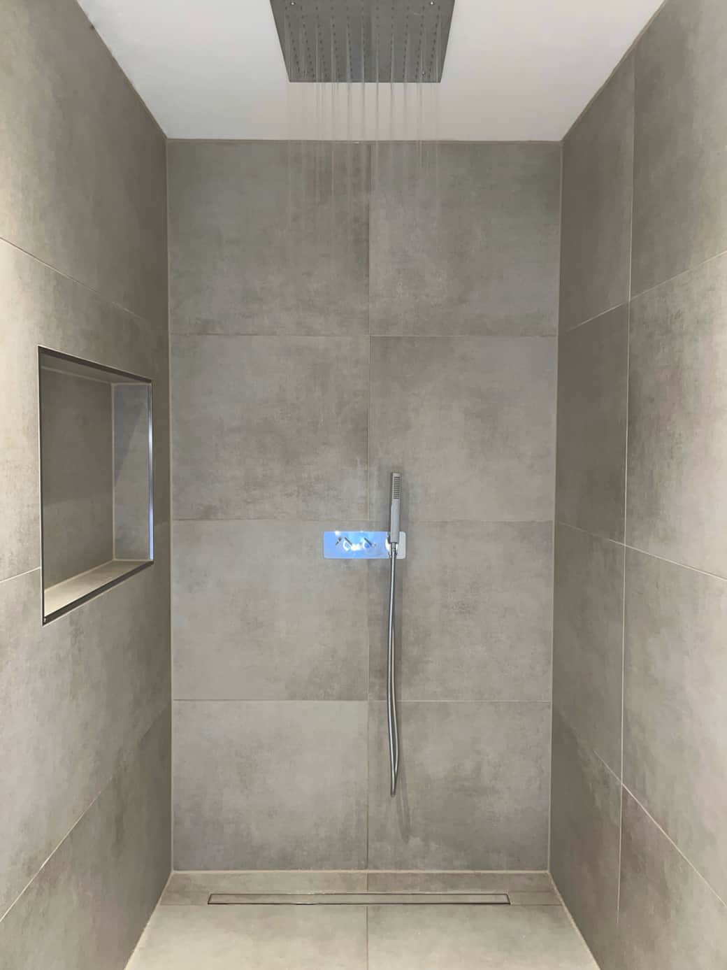 Walk-in-Wellness: Ebenerdige Regendusche mit großem Decken-Duschkopf – links eine Duschnische.