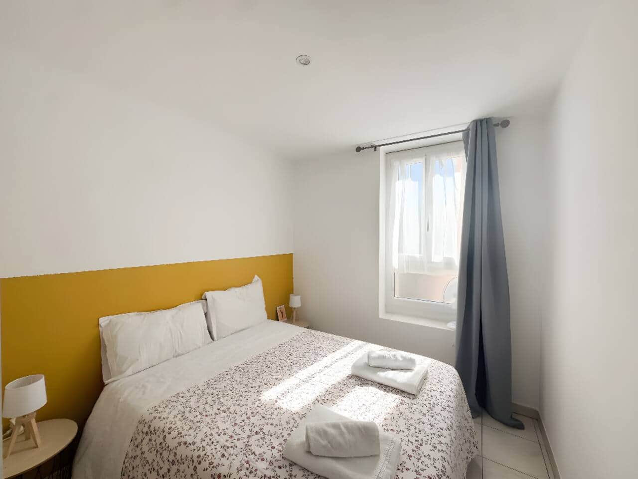 Votre chambre parentale douillette : Un lit queen-size avec literie neuve pour des nuits réparatrices après vos soins. Mur jaune moutarde, lumière apaisante et espace rangement. Parfaite pour les curistes en quête de sérénité. 
