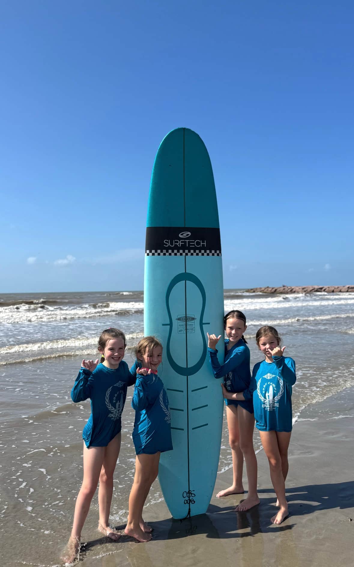 Kids posing with a surfboard at Ohana Surf Camp in Galveston